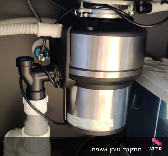 מתקן טוחן אשפה מתחת לכיור עם צינורות חיבור
